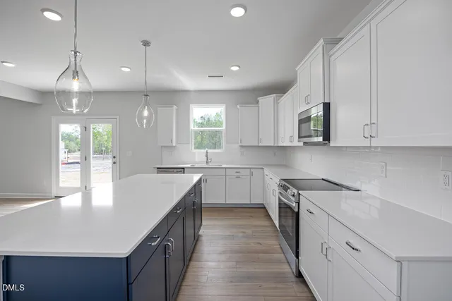 a kitchen with kitchen island granite countertop a sink a counter space appliances and cabinets