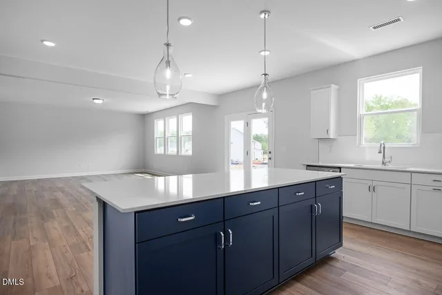 a kitchen with kitchen island granite countertop a sink window and wooden floor