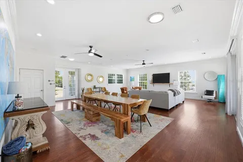 a living room with furniture floor to ceiling window hardwood floor and a flat screen tv