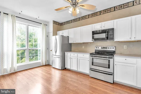 a kitchen with stainless steel appliances a stove a sink and white cabinets