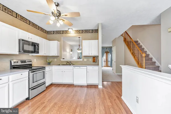 a kitchen with granite countertop a stove top oven a sink dishwasher a dining table and chairs with wooden floor