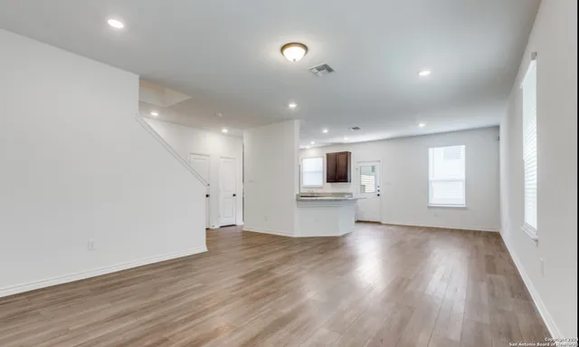a view of empty room with wooden floor and windows