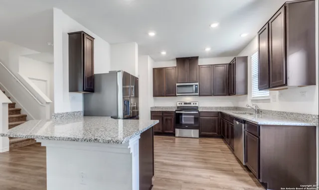 a kitchen with stainless steel appliances granite countertop refrigerator a sink a stove a microwave and wooden cabinets