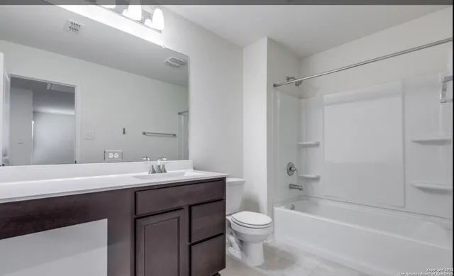 a bathroom with a sink a toilet a mirror and shower