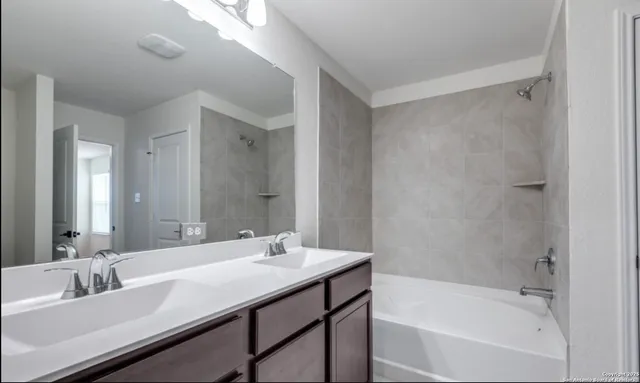 a bathroom with a bathtub shower sink vanity and mirror