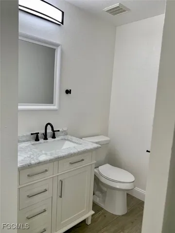 a bathroom with a granite countertop toilet sink and mirror
