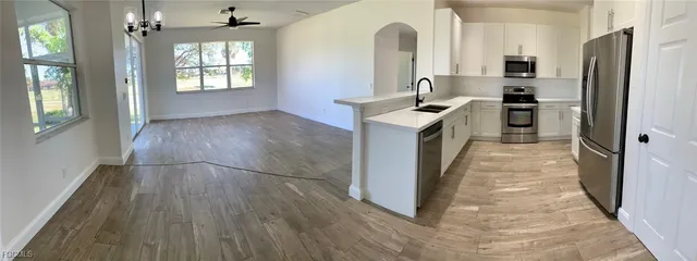 a kitchen with kitchen island a counter top space a sink a refrigerator and wooden floors