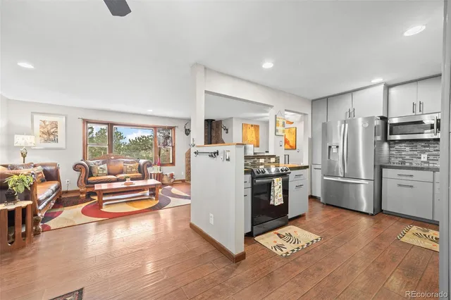 a kitchen with stainless steel appliances a refrigerator a stove a sink dishwasher a oven with white cabinets and wooden floor