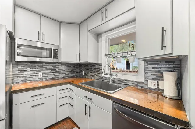 a kitchen with granite countertop a sink stainless steel appliances and cabinets