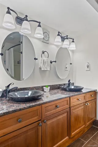 a bathroom with a granite countertop double vanity sink and mirror