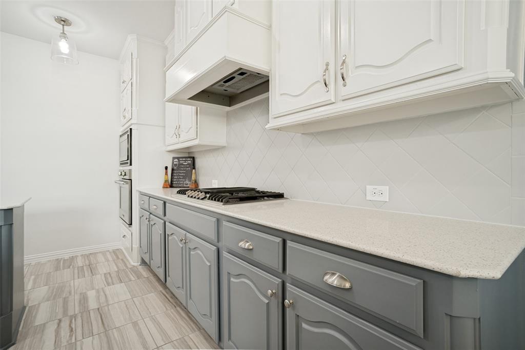 1461 Ramsbury Lane Prosper, TX 75078 - Photo 7 of 30 Kitchen featuring white upper cabinetry, gray lower cabinetry, light-toned countertops, a white diamond-patterned tile backsplash, and wood-finish flooring