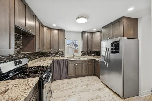 a kitchen with stainless steel appliances granite countertop a refrigerator a sink and a stove