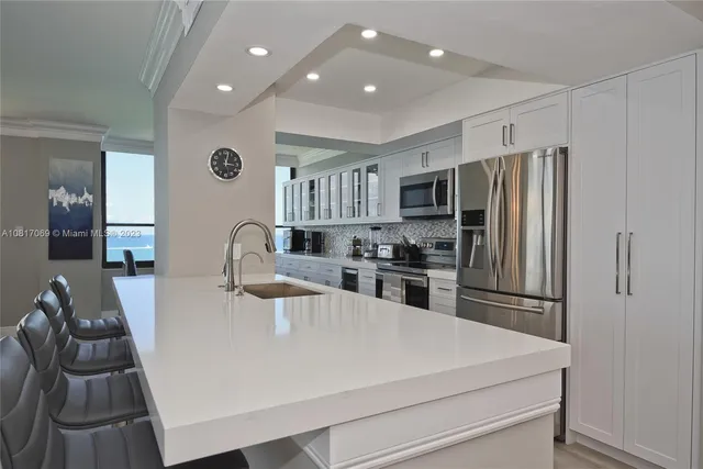 a kitchen with kitchen island a refrigerator stove and a sink