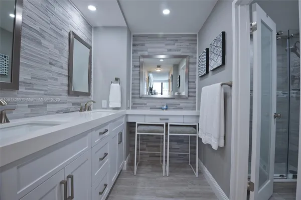 a spacious bathroom with a double vanity sink a mirror and a shower