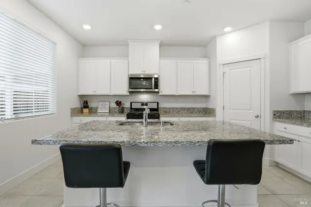a kitchen with granite countertop white cabinets sink and stainless steel appliances
