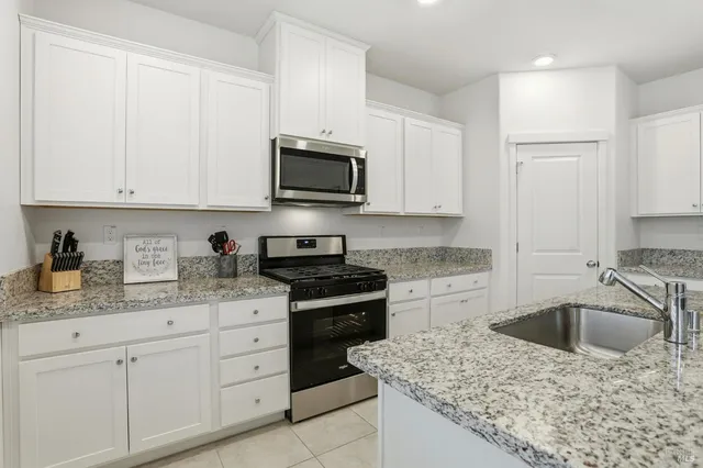 a kitchen with granite countertop a sink stove and cabinets