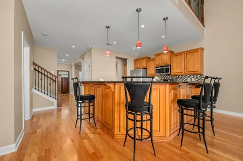 a kitchen with stainless steel appliances kitchen island granite countertop a table chairs and a wooden floor