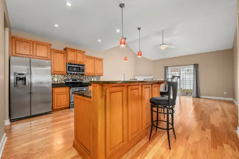 a kitchen with stainless steel appliances granite countertop a refrigerator a stove and a wooden cabinets