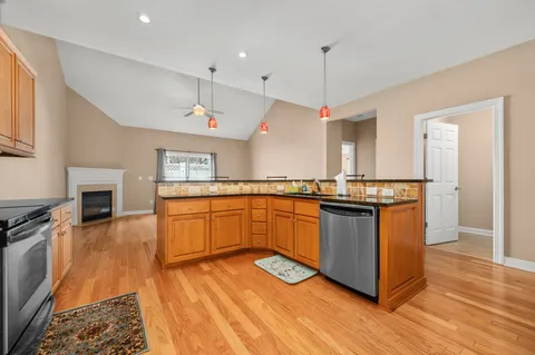 a kitchen with stainless steel appliances granite countertop a stove and a wooden floors