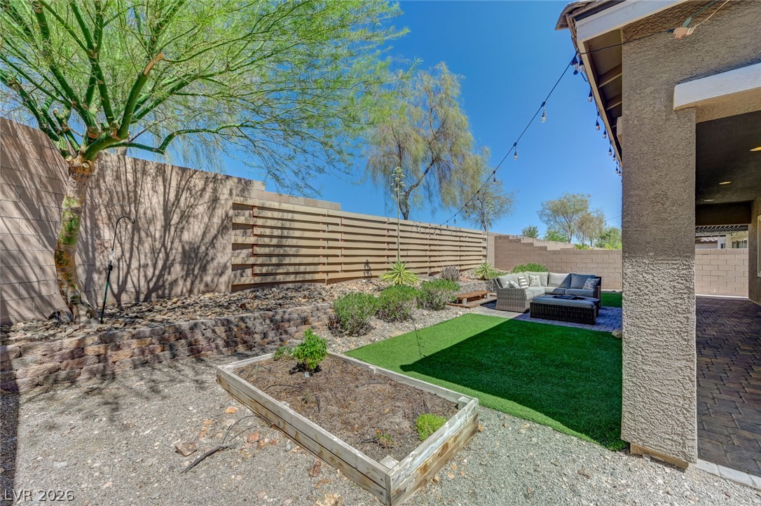 8197 Riley Love Street Las Vegas, NV 89139 - Photo 40 of 48 An inviting backyard oasis offers a comfortable outdoor seating area, artificial turf, and diverse landscaping under a clear sky.