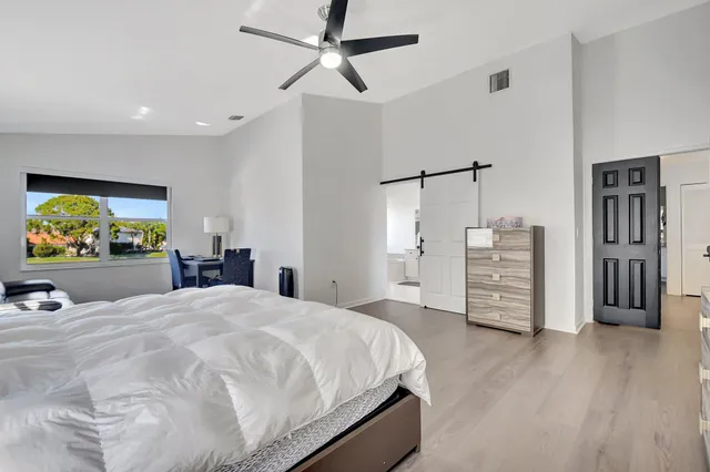 a spacious bedroom with a bed and a flat screen tv