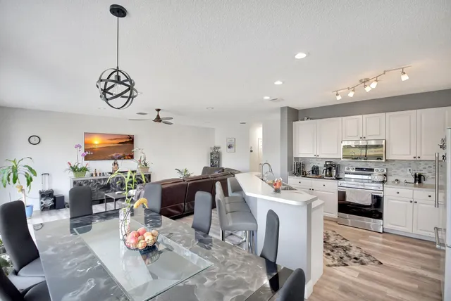 a kitchen with stainless steel appliances kitchen island granite countertop a sink dishwasher stove and white cabinets with wooden floor