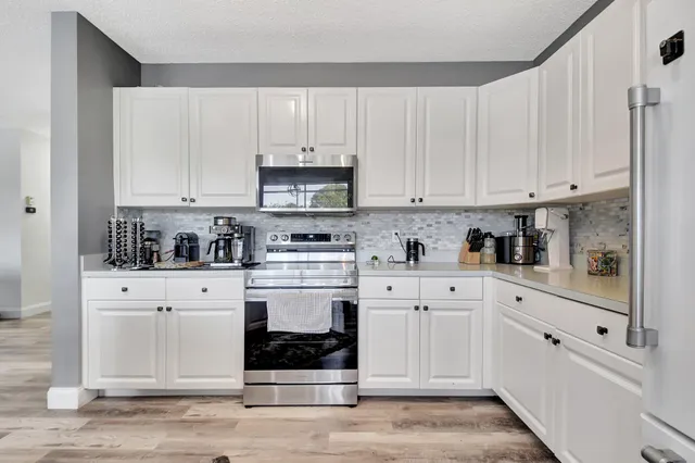 a kitchen with stainless steel appliances granite countertop a stove and white cabinets