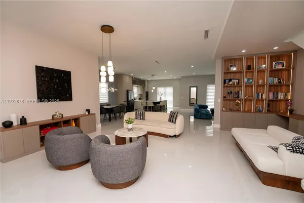 a living room with furniture a flat screen tv and a chandelier