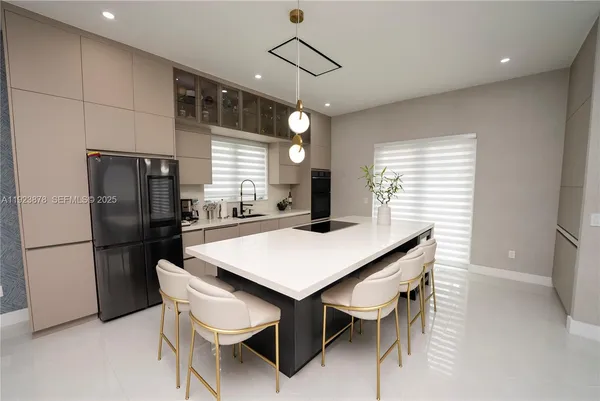a kitchen with stainless steel appliances kitchen island a table chairs and refrigerator