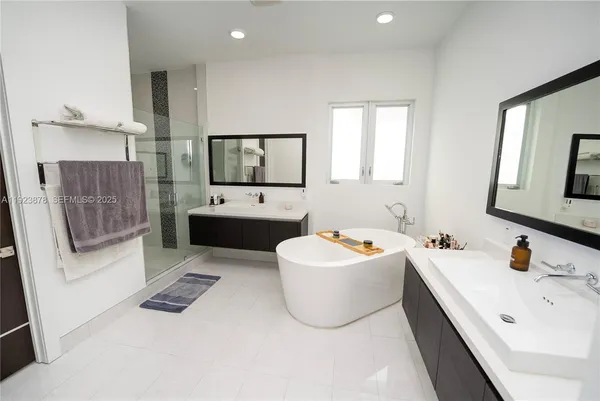 a bathroom with a double vanity sink mirror and bathtub