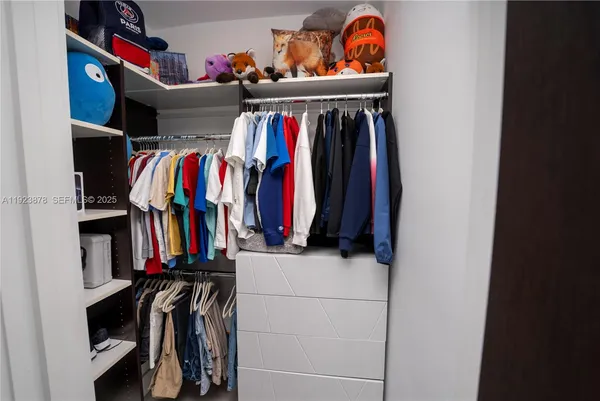 a view of walk in closet with clothes and shoes
