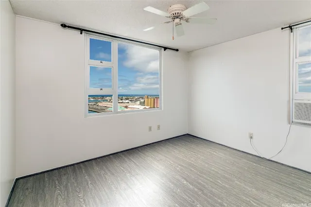 an empty room with wooden floor fan and windows