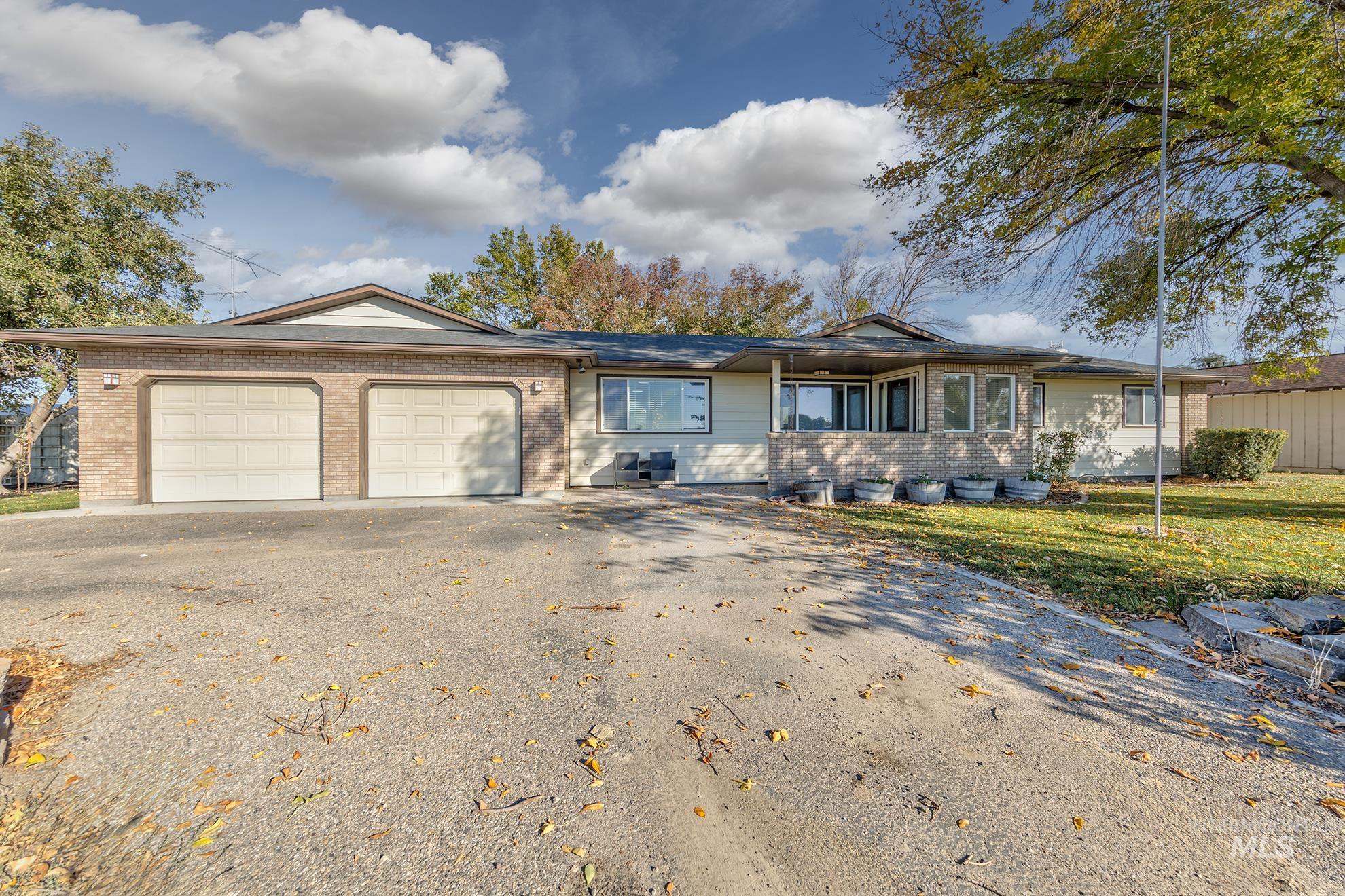 Ranch-style house with asphalt driveway, brick siding, a garage, and a front lawn