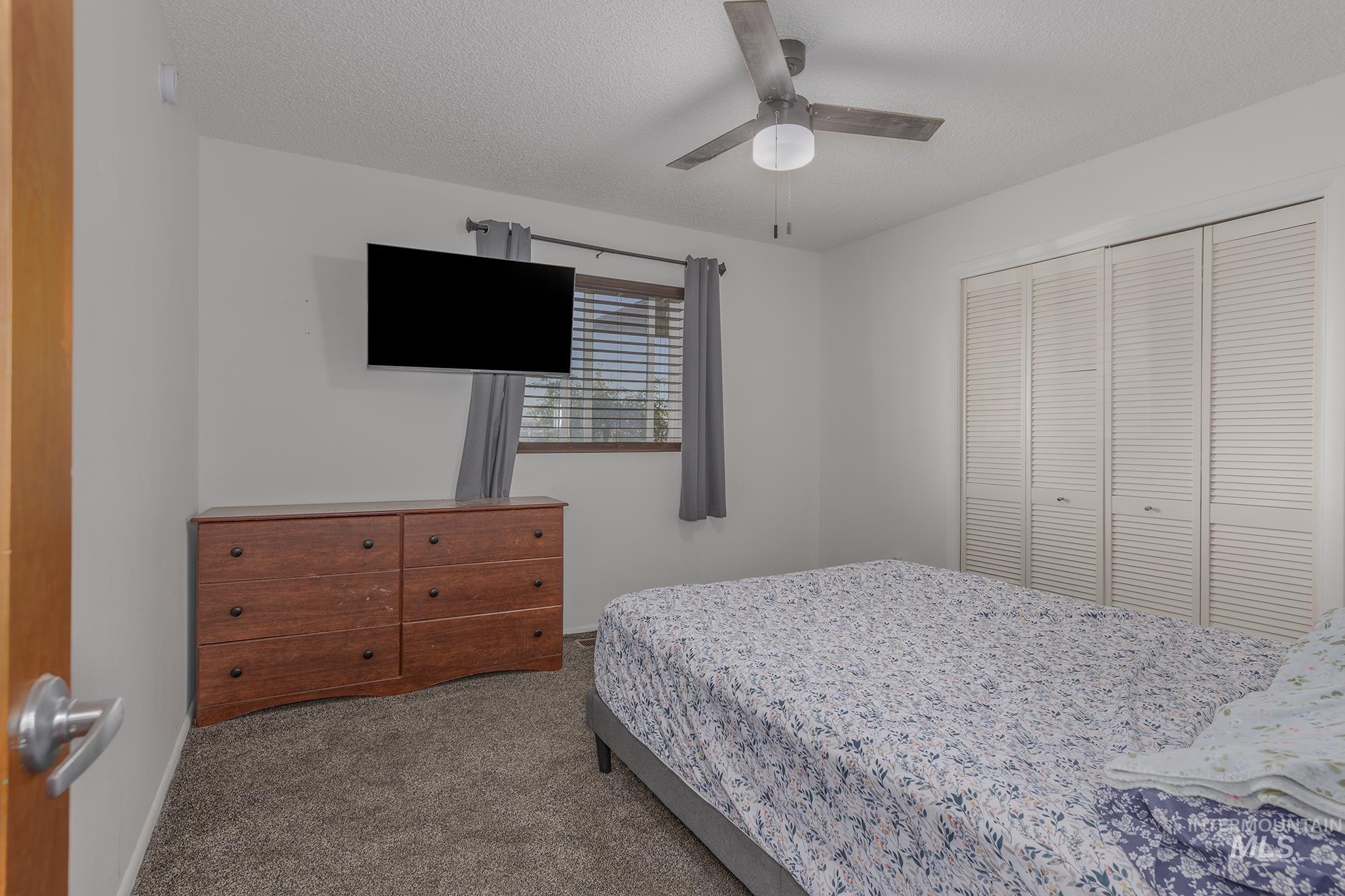 710 North 5th Street Nyssa, OR 97913 - Photo 14 of 36 Carpeted bedroom with a closet, ceiling fan, and a textured ceiling