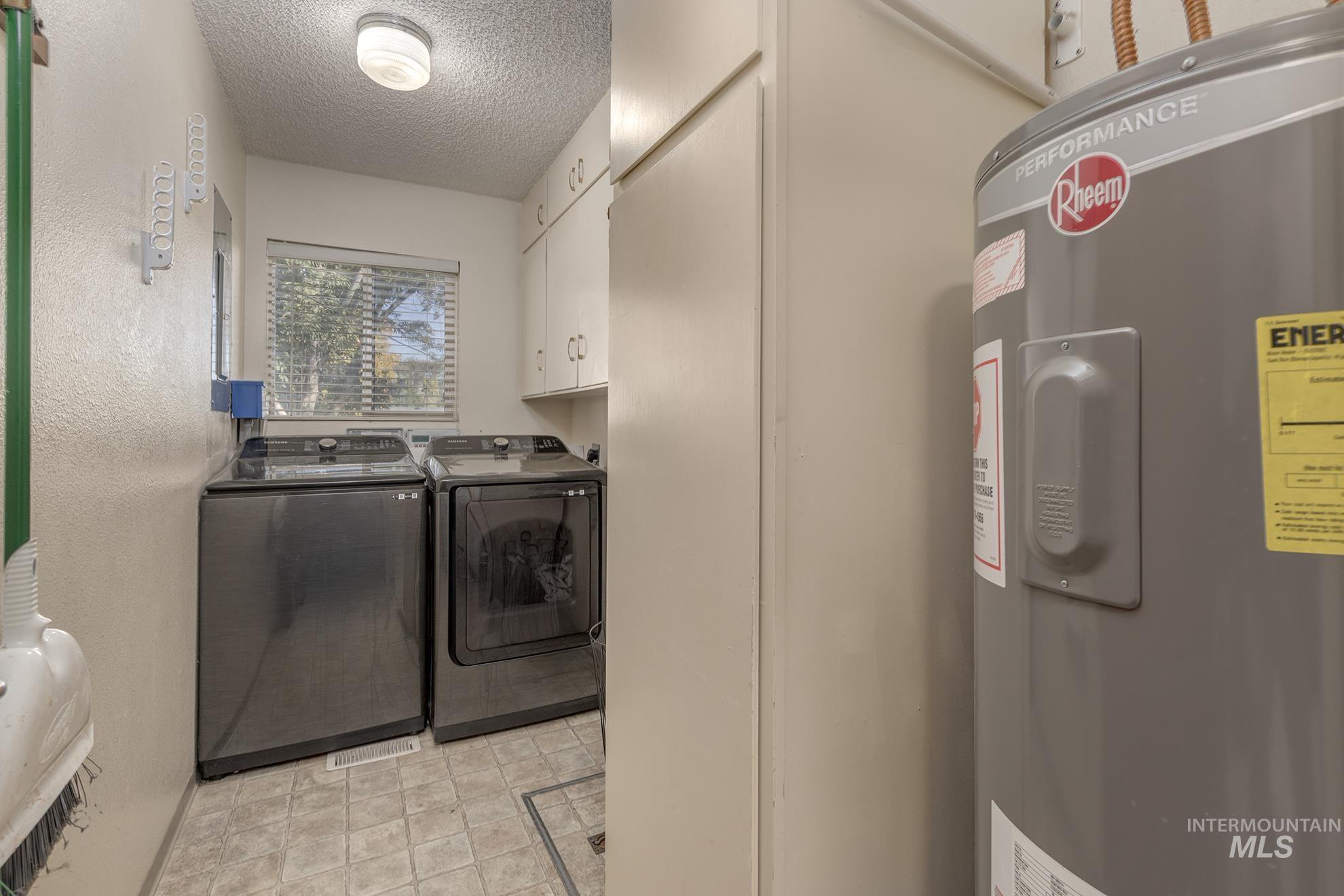 710 North 5th Street Nyssa, OR 97913 - Photo 19 of 36 Washroom with electric water heater, a textured ceiling, cabinet space, washing machine and dryer, and a textured wall