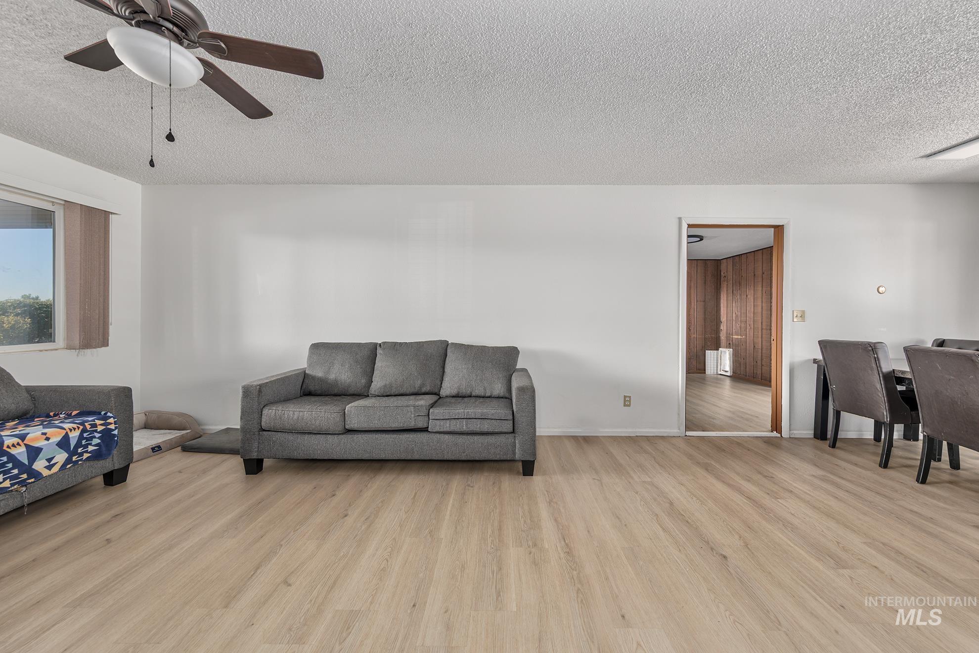 710 North 5th Street Nyssa, OR 97913 - Photo 7 of 36 Living room featuring light wood finished floors, a textured ceiling, and a ceiling fan