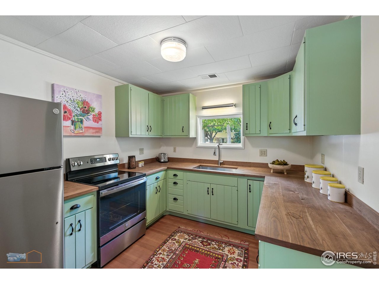 8522 Valmont Road Boulder, CO 80301 - Photo 32 of 49 a kitchen with green cabinets a stove a sink and a window