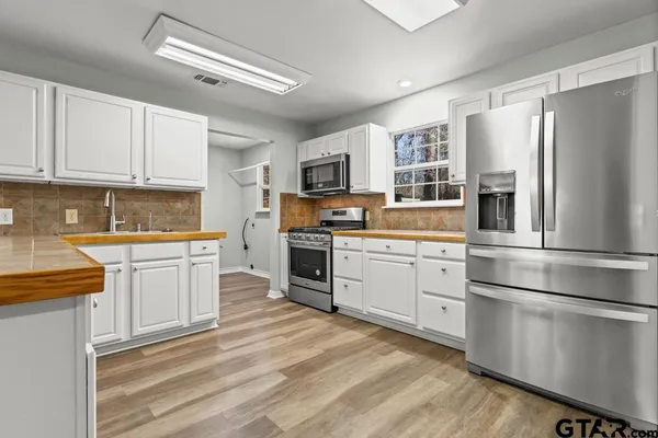 a kitchen with granite countertop white cabinets and stainless steel appliances