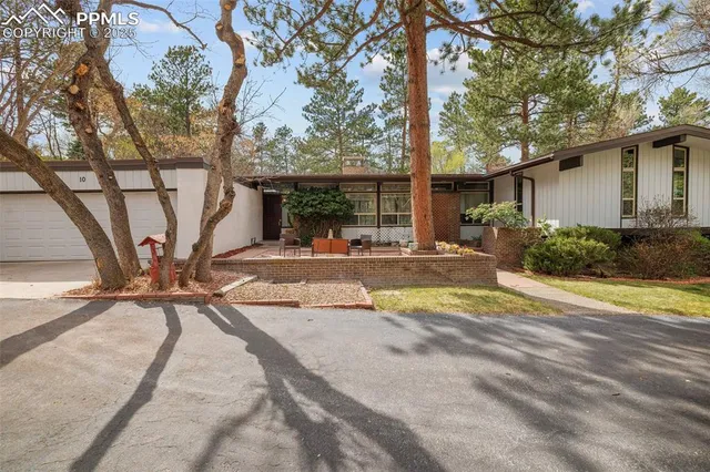 front view of a house with table and chairs under a large tree