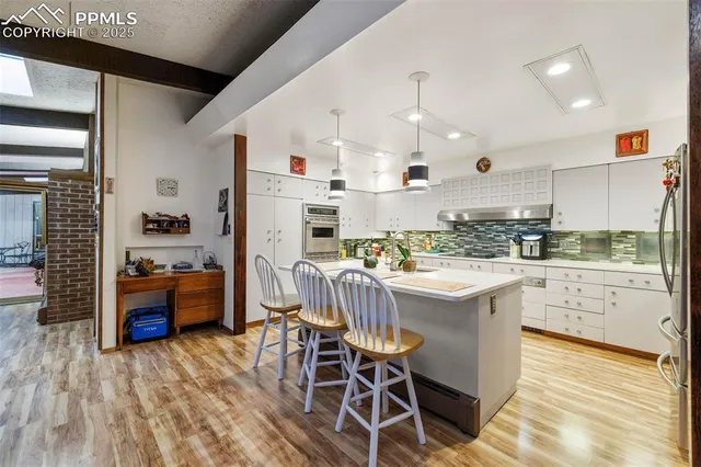 a kitchen with a sink appliances and wooden floor