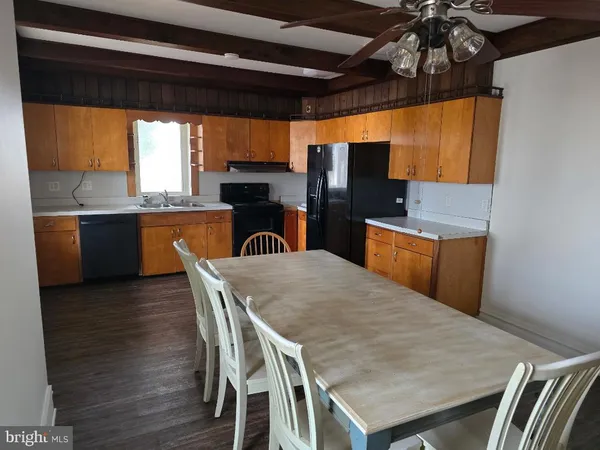 a kitchen with stainless steel appliances kitchen island granite countertop a table chairs and a wooden floor