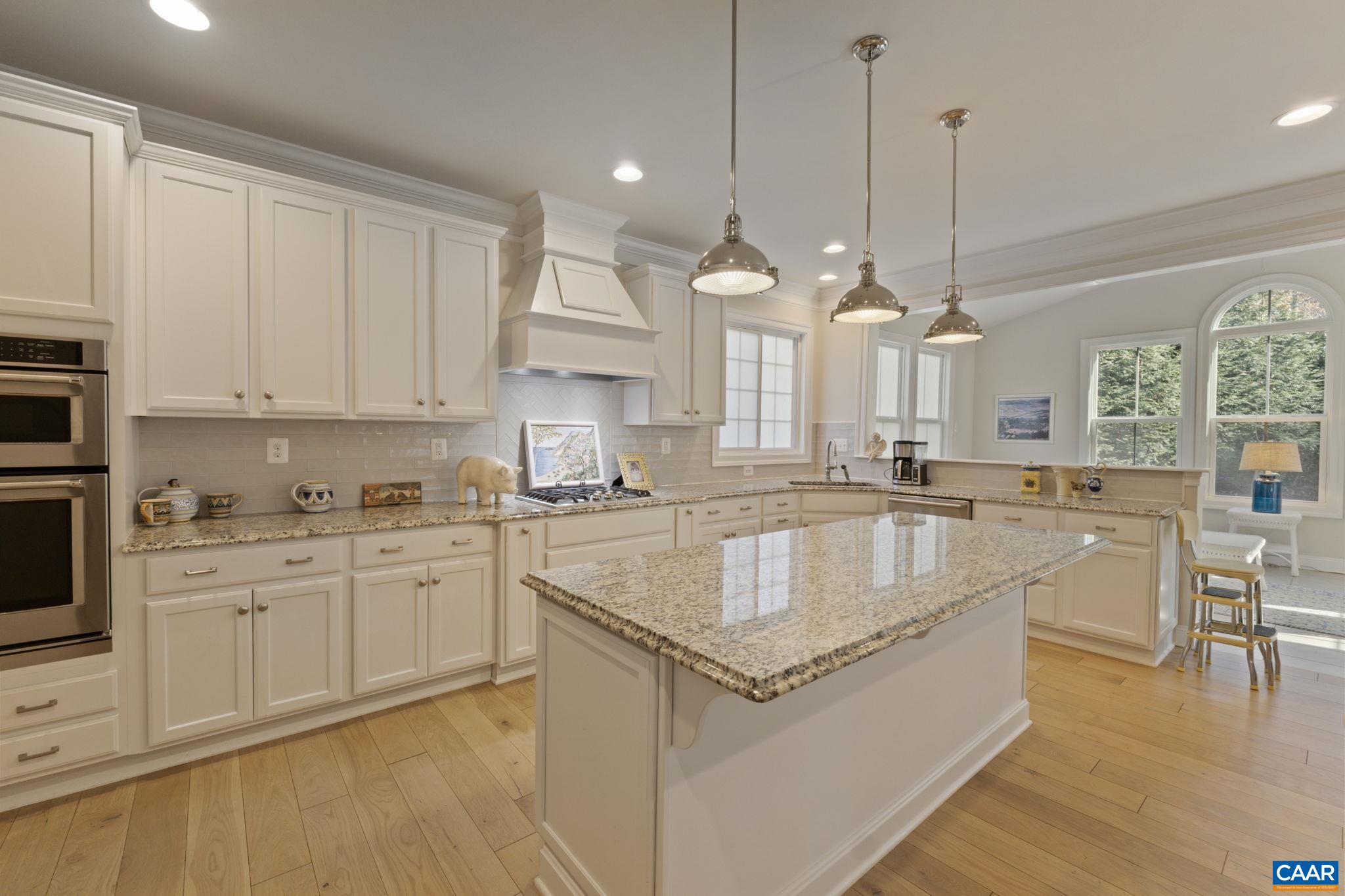 3650 Newbridge Road Keswick, VA 22947 - Photo 21 of 58 a large kitchen with kitchen island granite countertop a stove a sink a dining table and chairs with wooden floor