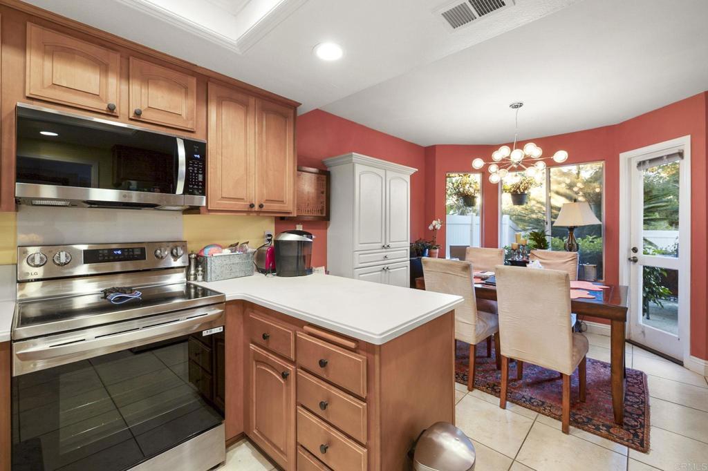 4683 Majorca Way Oceanside, CA 92056 - Photo 15 of 55 a kitchen with a stove a sink dishwasher a microwave oven with a dining table and chairs with wooden floor