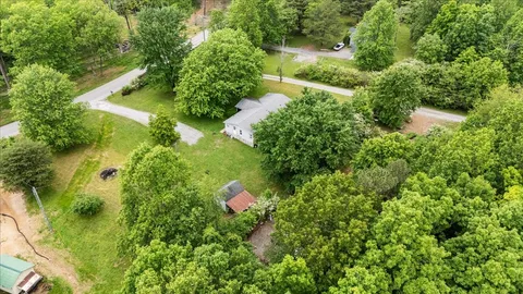 an aerial view of residential house with outdoor space and trees all around