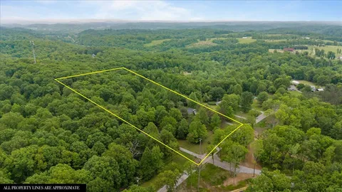 an aerial view of residential house with outdoor space and trees all around