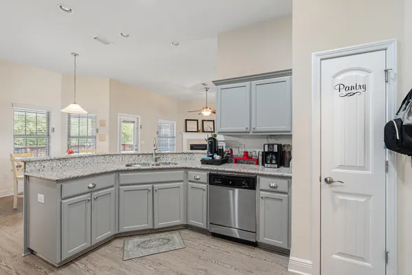 a kitchen with a sink dishwasher a stove and white cabinets with wooden floor