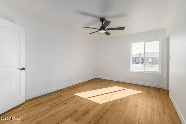 an empty room with wooden floor fan and windows