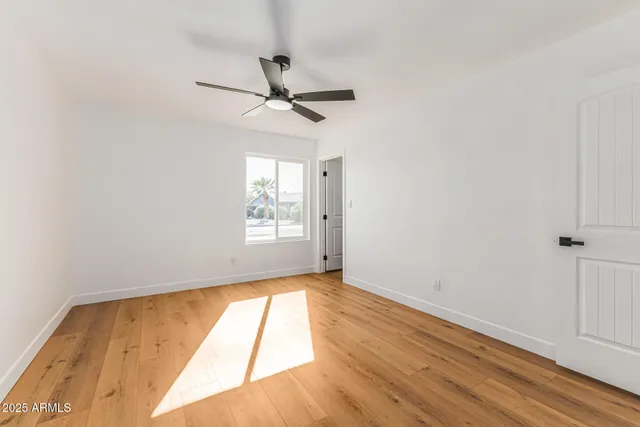 a view of empty room with wooden floor and fan