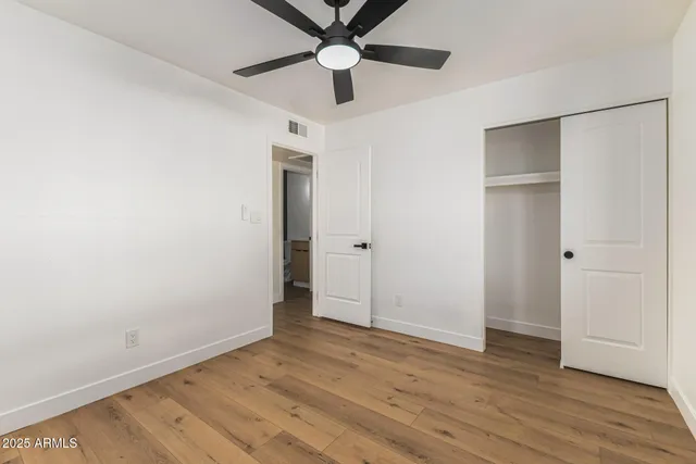 an empty room with wooden floor a ceiling fan and closet
