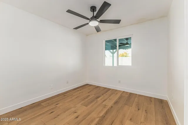 an empty room with a window and a ceiling fan